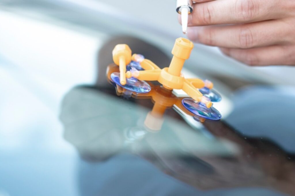 Nahaufnahme Autoglaser bei der Reparatur einer Windschutzscheibe eines Autos in einer Werkstatt. Glas für die Reparatur bohren